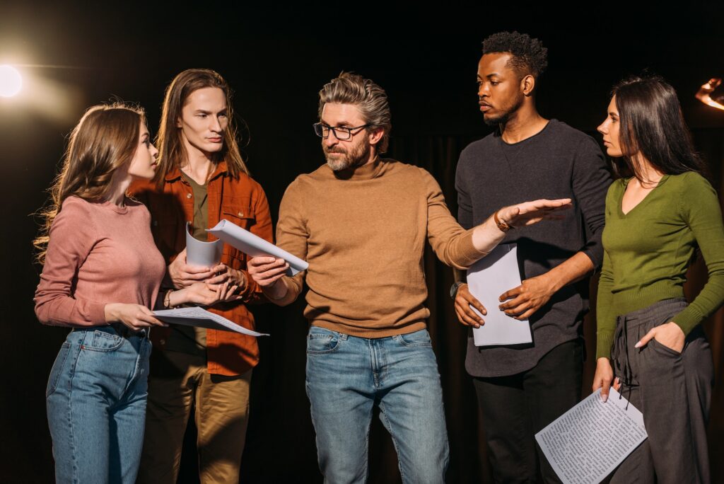 multiethnic actors and actresses rehearsing with theater director on stage